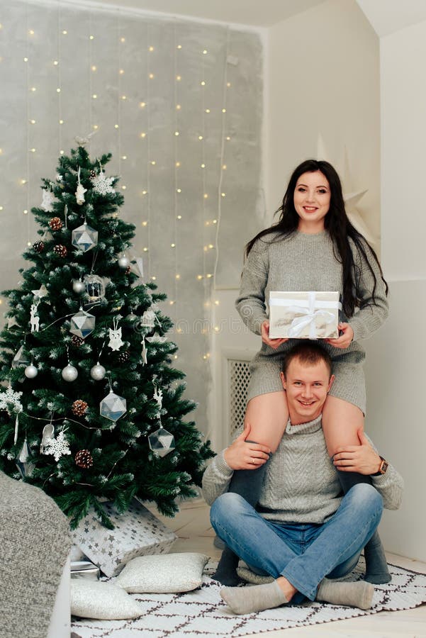 Young Couple In Love In Christmas Decor With Gifts And Christmas Tree